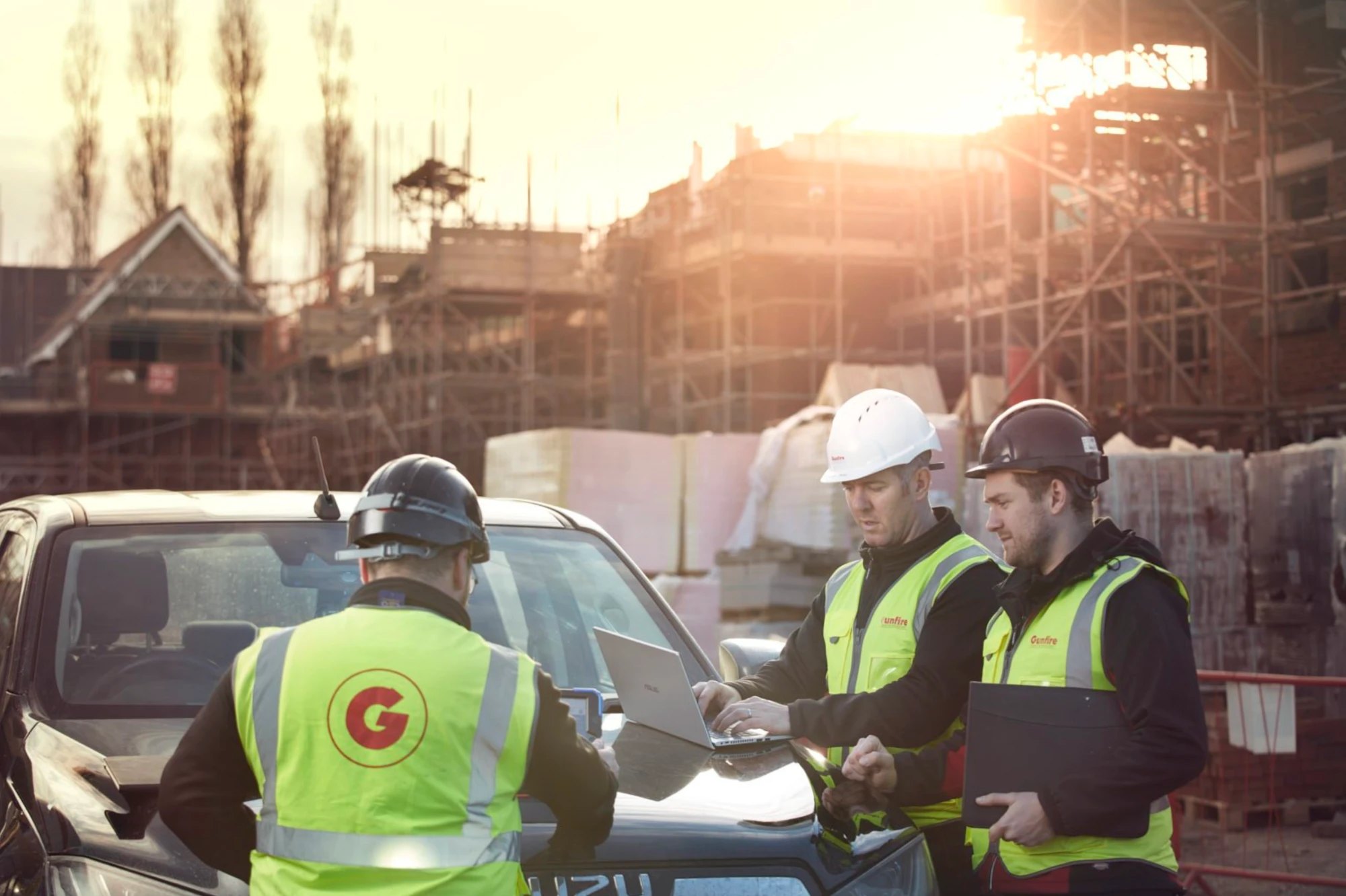 Gunfire site team checking plans at sunset